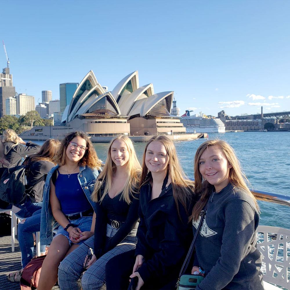 four young ladies relaxing at the bay with sydney opera house in the background